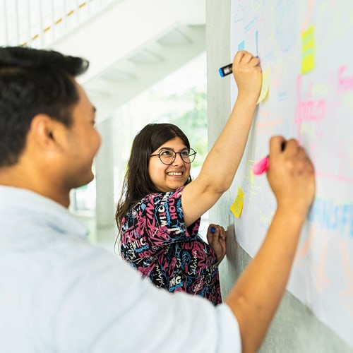 Zwei Personen schreiben auf ein White Board
